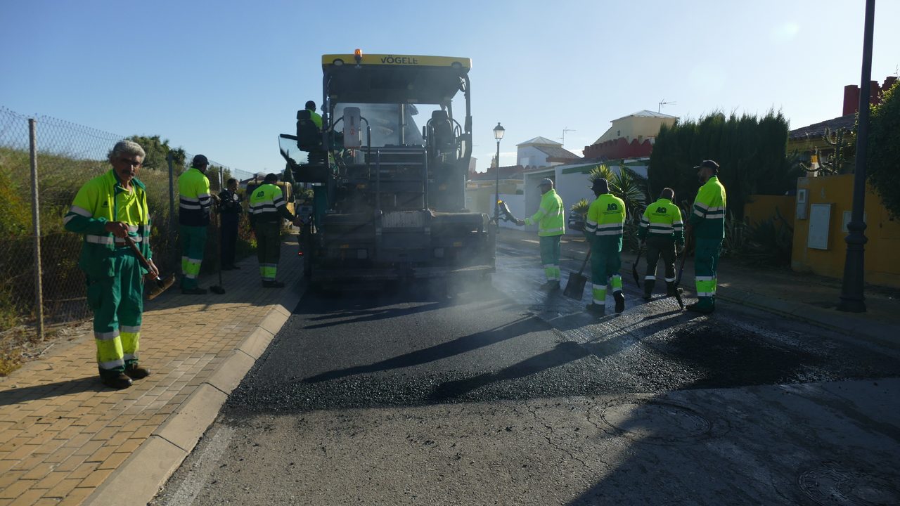Cuadrilla de operarios extendiendo aglomerado asfáltico en un vial del complejo.